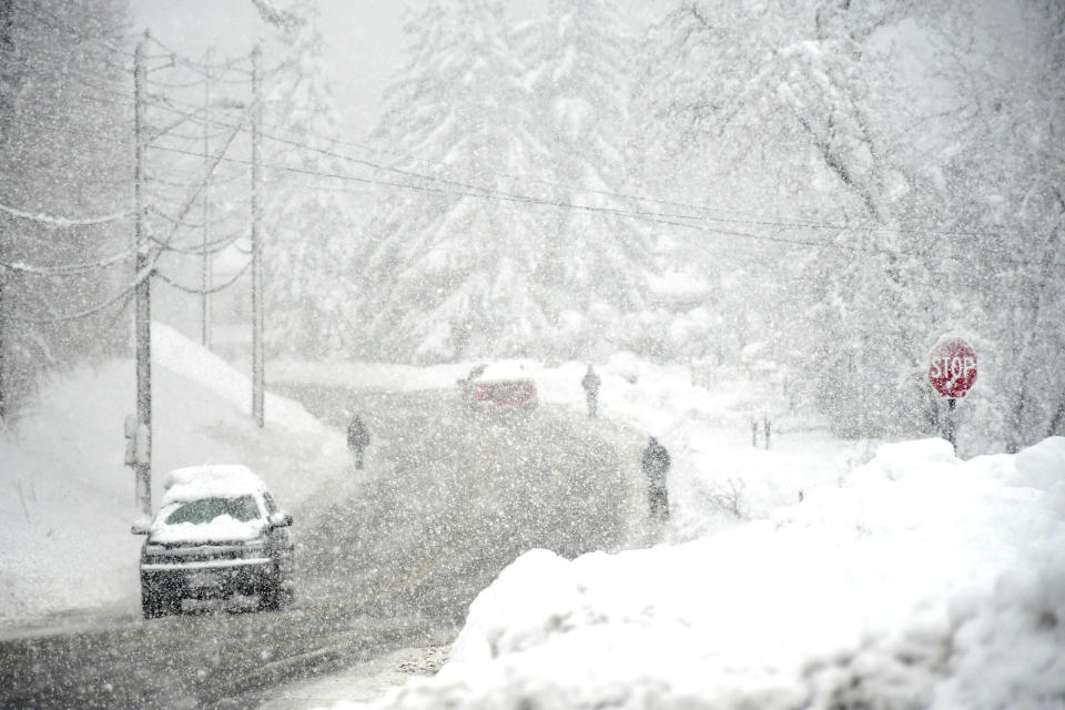 Pedestrians share the road with motorists on Route 2, on the Mohawk Trail, in North Adams, Mass., on Tuesday March 14, 2023, during a snowstorm. (Gillian Jones/The Berkshire Eagle via AP)