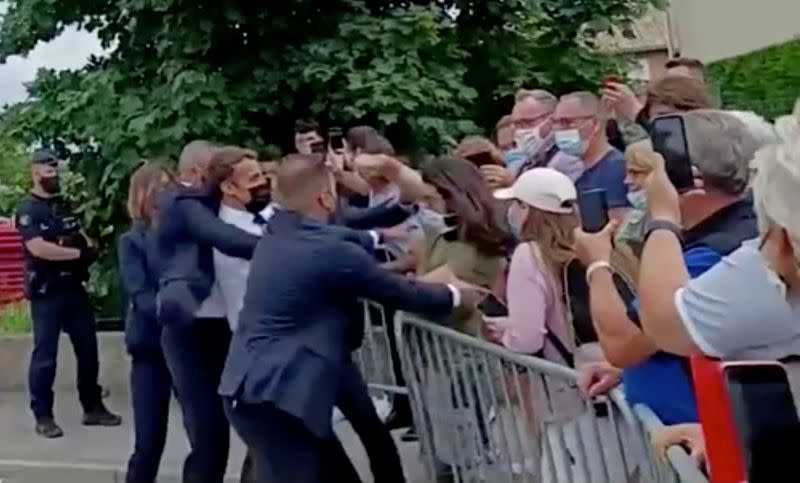 French President Emmanuel Macron is slapped in the face by a member of the public during a visit to Tain-l'Hermitage, France