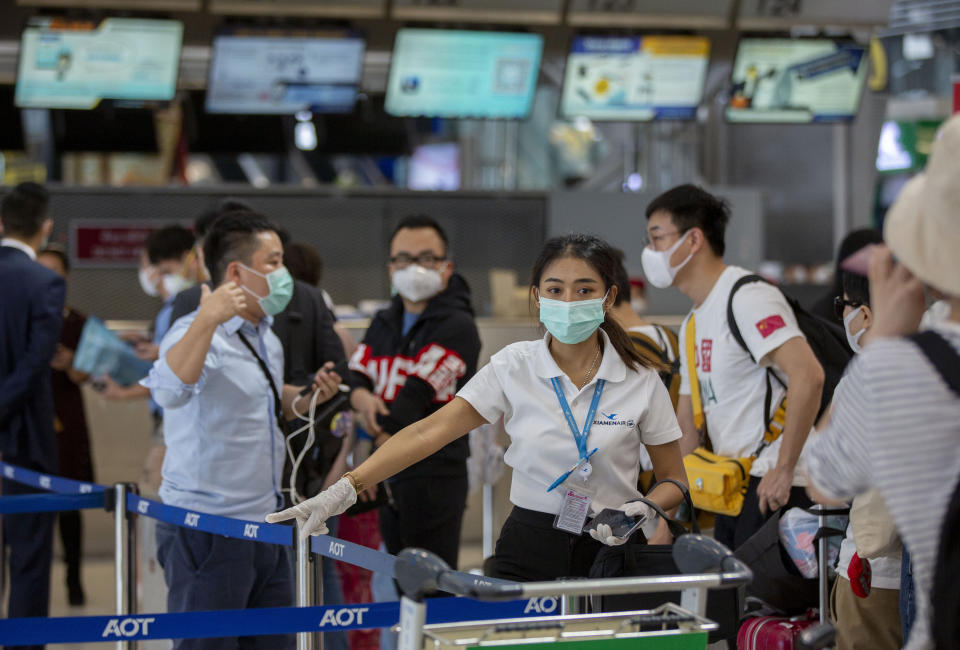 An airline staffer assists tourists from Wuhan, china, as they wait for a charter flight back to Wuhan at the Suvarnabhumi airport, Bangkok, Thailand, Friday, Jan. 31, 2020. A group of Chinese tourists who have been trapped in Thailand since Wuhan was locked down due to an outbreak of new virus returned to China on Friday. (AP Photo/Gemunu Amarasinghe)