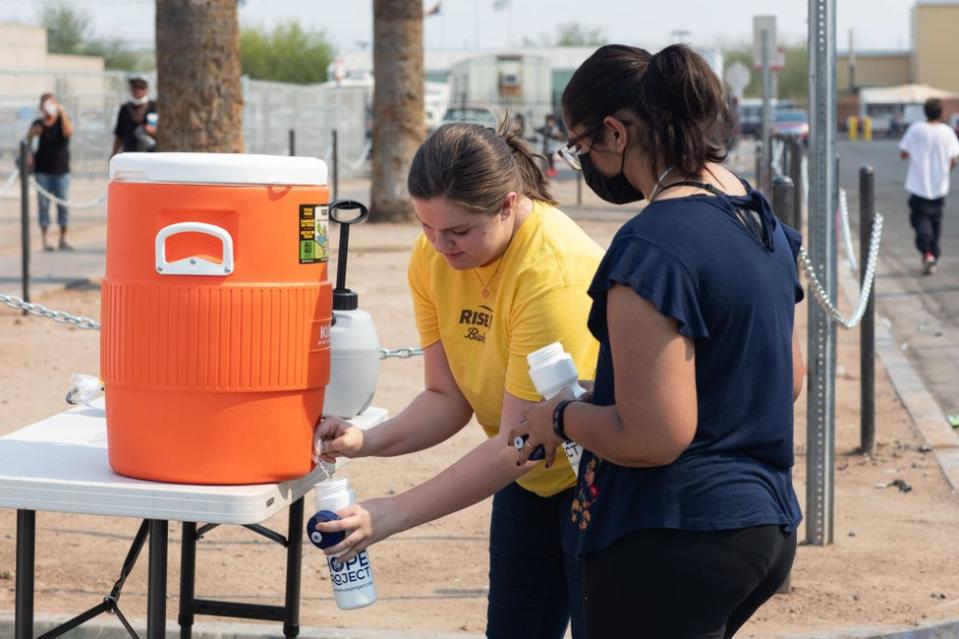 Las voluntarias Mackenzie Zollner y Lina Ali reparten agua a gente sin hogar en Phoenix, Texas, en junio de 2021.