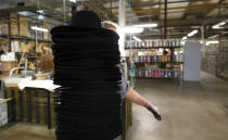 A woman holds a pile of hats inside Borsalino's hat factory, in Spinetta Marengo, near Alessandria, Italy, Thursday, Jan. 17, 2019. Borsalino's prized felt hats are handmade by 80 workers in its Piemonte factory, many who have worked there for decades, with original machinery that use hot water and steam to transform rabbit fur into highly prized felt, that is formed into clochards, dyed and molded by hand to create the latest styles. (AP Photo/Antonio Calanni)