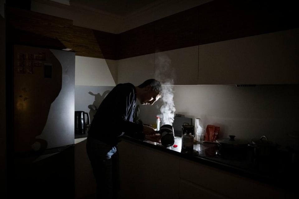 IT worker Igor, who normally uses an electric hob, makes tea using a camping stove in his apartment block in near total darkness during a scheduled power cut in Kyiv on Nov. 6, 2022. (Ed Ram/Getty Images)