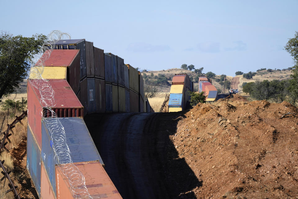 A long row of double-stacked shipping contrainers provide a new wall between the United States and Mexico in the remote section area of San Rafael Valley, Ariz., Thursday, Dec. 8, 2022. Work crews are steadily erecting hundreds of double-stacked shipping containers along the rugged east end of Arizona’s boundary with Mexico as Republican Gov. Doug Ducey makes a bold show of border enforcement even as he prepares to step aside next month for Democratic Governor-elect Katie Hobbs. (AP Photo/Ross D. Franklin)