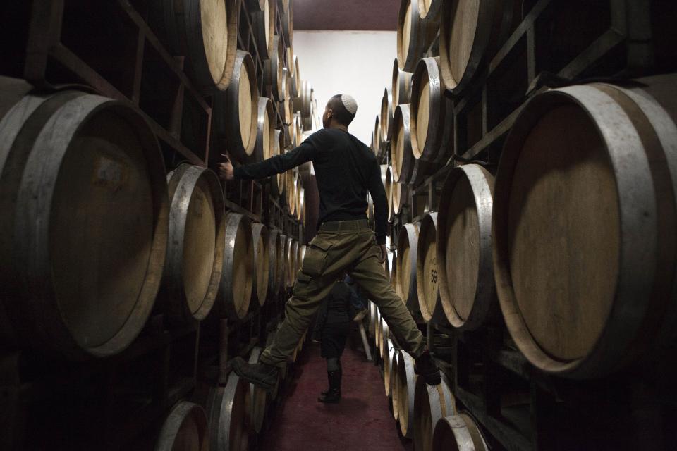 In this Tuesday, Feb. 11, 2014 photo, Israeli workers inspects barrels in a winery in the West Bank settlement of Psagot. With Israel mired in a struggle to combat growing calls in Europe to boycott Israeli products and businesses with ties to the settlements, a quieter, subtler and more informal campaign is taking place at home among Israelis themselves. The Palestinians complain that the growing settler population makes it ever more difficult to partition the land. The issue has taken center stage in ongoing U.S.-mediated peace talks. (AP Photo/Dan Balilty)