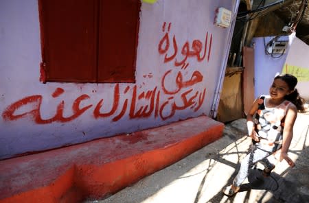 A girl walks past a slogan at Burj al-Barajneh refugee camp in Beirut