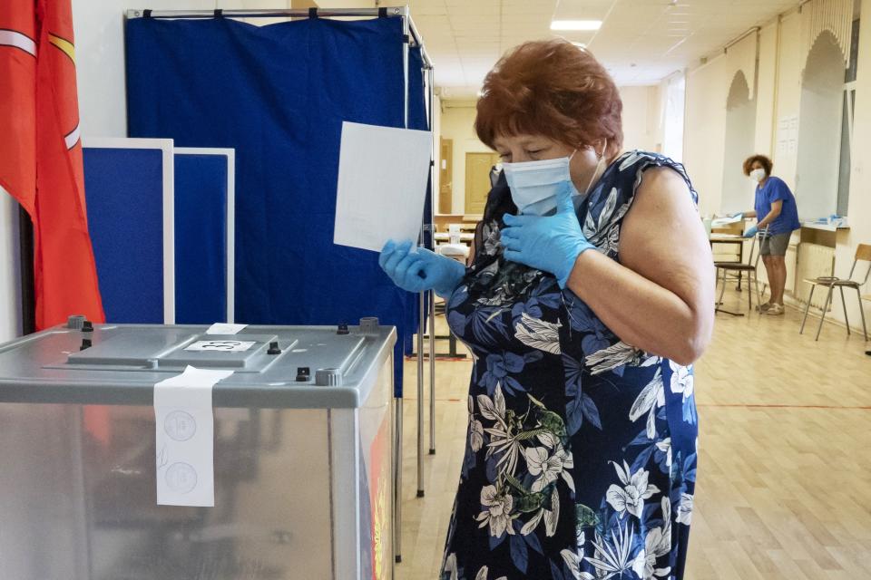 FILE - In this June 25, 2020, file photo, a voter wearing a face mask and protective gloves to protect against coronavirus walks to cast her ballot at a polling station in St. Petersburg, Russia. Russian President Vladimir Putin is just a step away from bringing about the constitutional changes that would allow him to extend his rule until 2036. The vote that would reset the clock on Putin’s tenure in office and allow him to serve two more six-year terms is set to wrap up Wednesday, July 1, 2020. (AP Photo/Dmitri Lovetsky, File)