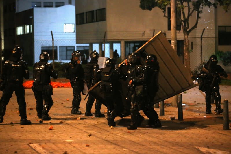 Riot police hold an improvised barricade while demonstrators protest at the National University as a national strike continues in Bogota