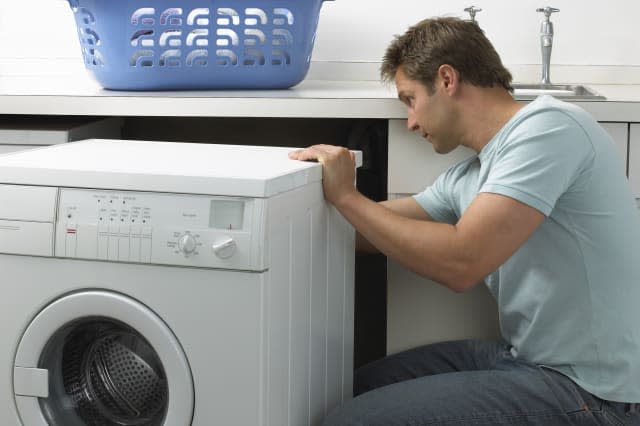 Man in a Kitchen Repairing a Washing Machine