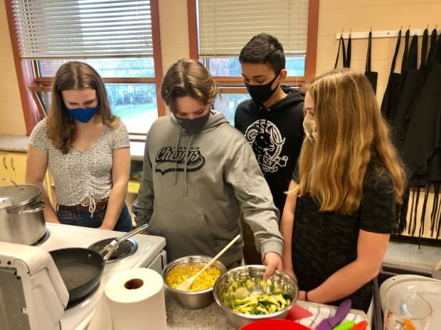 The students are making succotash with fresh green and yellow beans and corn.