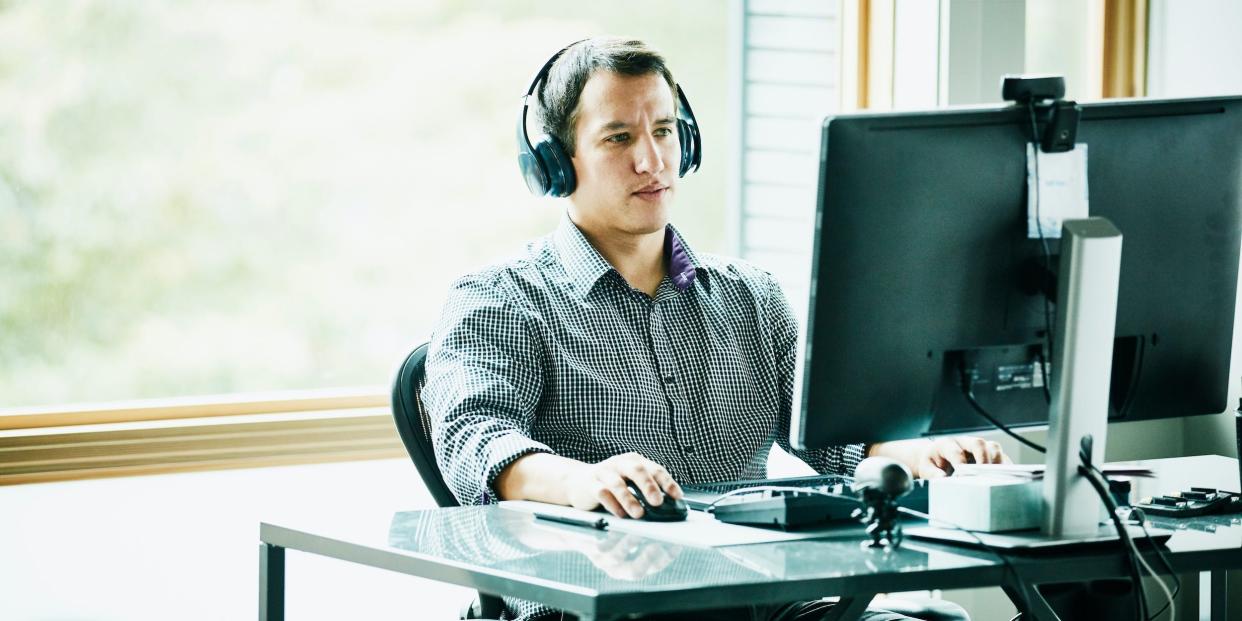 business professional working at office desktop computer headphones