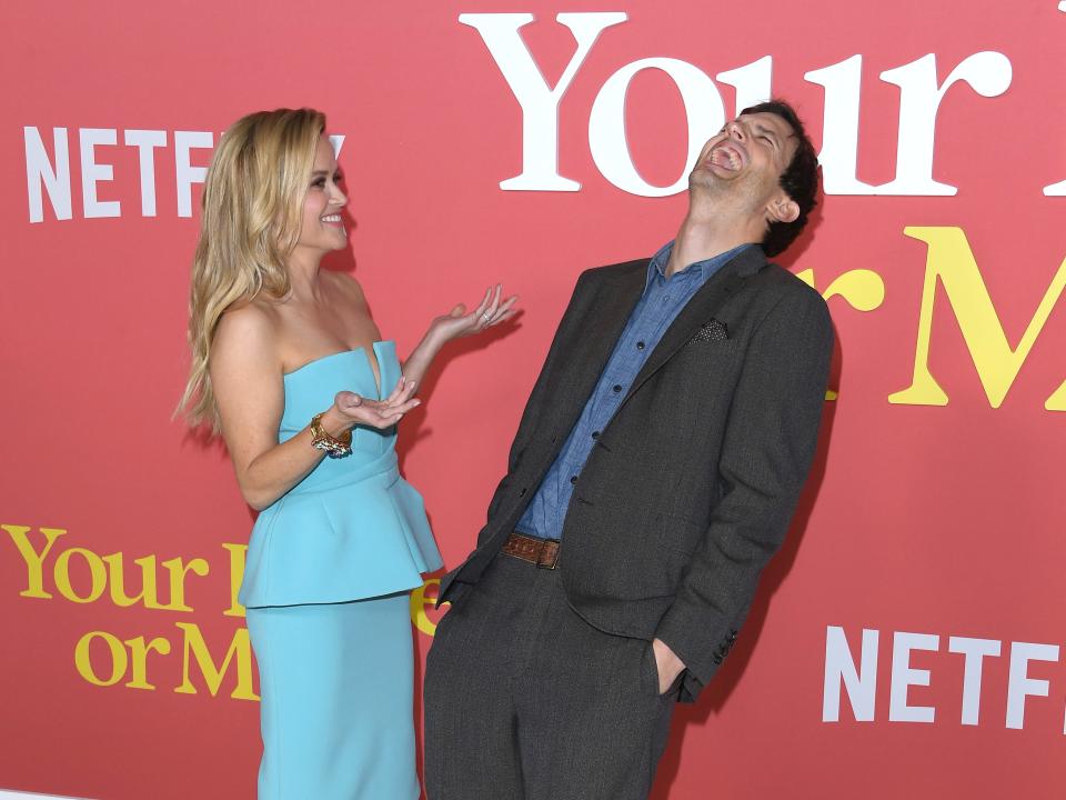 reese witherspoon and ashton kutcher together on the your place or mine red carpet. reese is turned towards ashton with her hands held out, as if she's just told a joke, while ashton is bent over laughing heartily