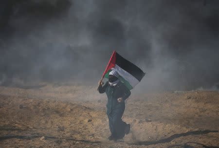 A demonstrator holds a Palestinian flag during a protest at the Israel-Gaza border in the southern Gaza Strip July 13, 2018. REUTERS/Ibraheem Abu Mustafa