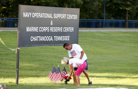 Glenna and Steve Mooneyham place flags and flowers at a sign leading to the Naval Operational Support and Marine Corps Reserve Center in Chattanooga, Tennessee July 16, 2015. REUTERS/Tami Chappell