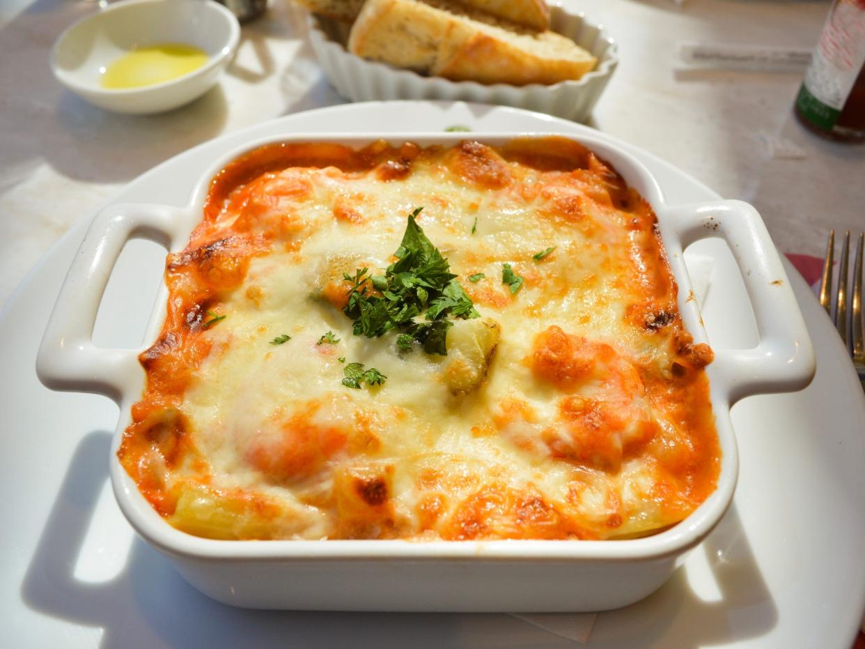 Lasagna in white pan on plate at restaurant