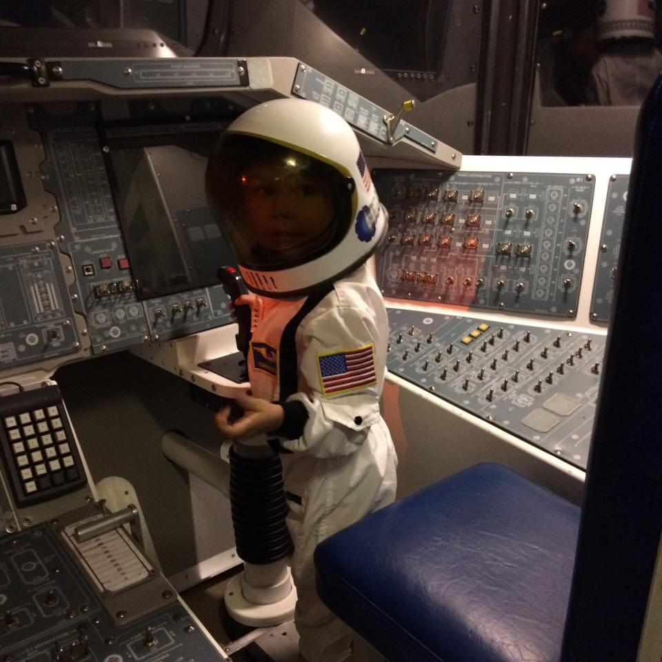 Felicity-John Pederson's grandson Jack Scanlan poses for a photo inside the Inspiration Mock Orbiter while wearing a space suit.