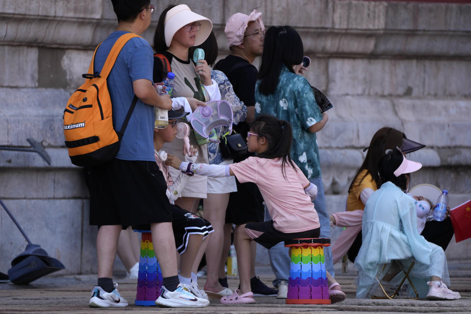 Visitors cooling themselves with electric fans line up in the shade to enter the Forbidden City on a sweltering day in Beijing, Friday, July 7, 2023. Earth's average temperature set a new unofficial record high on Thursday, the third such milestone in a week that already rated as the hottest on record. (AP Photo/Andy Wong)