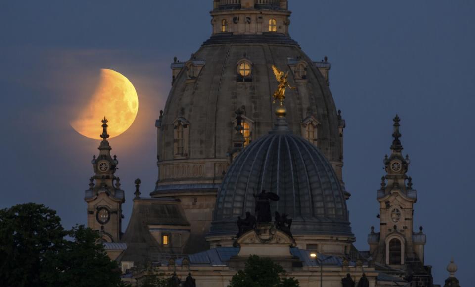 The partially eclipsed moon sets behind a church.