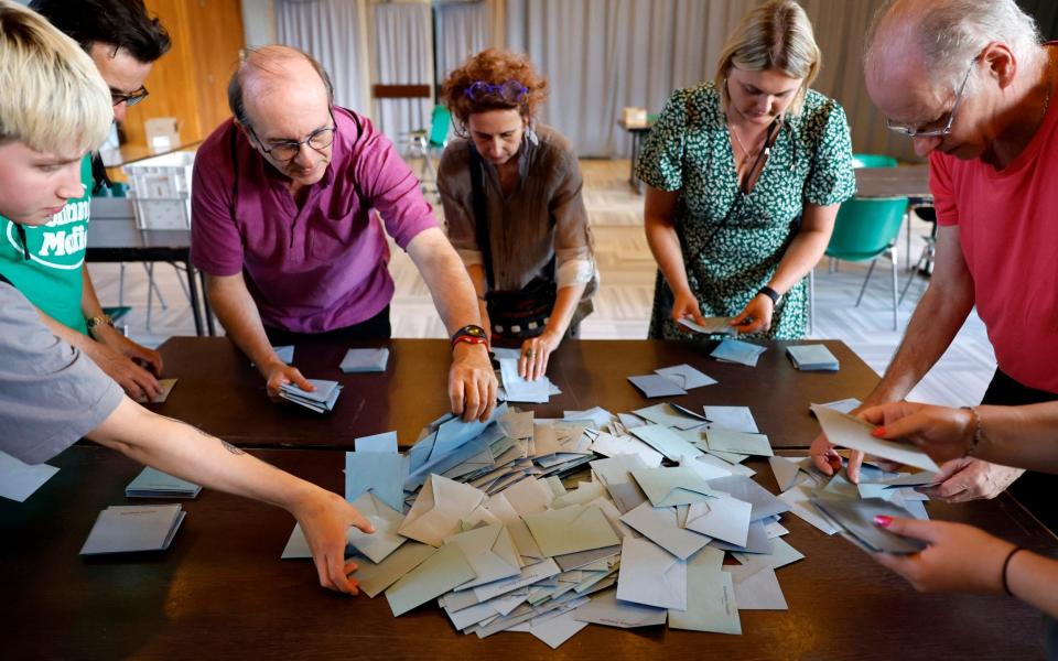 A group of poll workers sorts through a pile of ballot papers