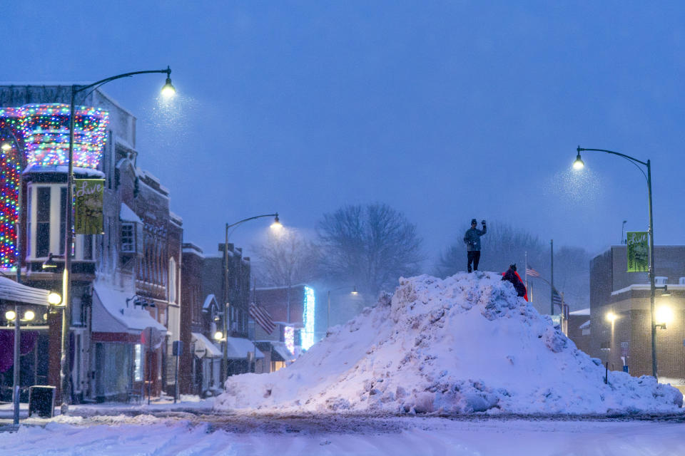 People stand on an large snow pile in Oskaloosa, Iowa, Tuesday, Jan. 9, 2024. Iowa Republicans will likely confront temperatures dipping below zero degrees Fahrenheit next week when they kick off the 2024 election cycle. The record-breaking forecast could complicate candidates' hopes of making their own history in the state's leadoff presidential caucuses. (AP Photo/Andrew Harnik)