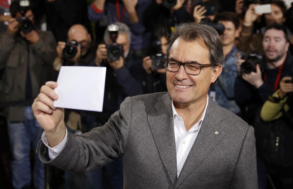 Catalan President Artur Mas holds up his ballot while voting in a symbolic independence vote in Barcelona, November 9, 2014. Secessionist-minded politicians helped by cultural organisations and thousands of volunteers organised the informal vote after Spain's High Court issued an injunction preventing a formal but non-binding referendum. REUTERS/Paul Hanna (SPAIN - Tags: POLITICS SOCIETY ELECTIONS)