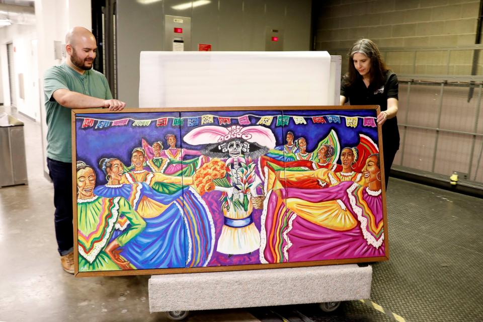 Nan Prince, MDAH director of collections, works with Hattiesburg artist Hector Boldo to unveil one of his paintings that will be added to the Mississippi Department of Archives collection.