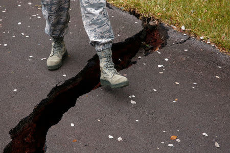 A soldier of the Hawaii National Guard steps over a crack in a road in Leilani Estates during ongoing eruptions of the Kilauea Volcano in Hawaii, U.S., May 18, 2018. REUTERS/Terray Sylvester