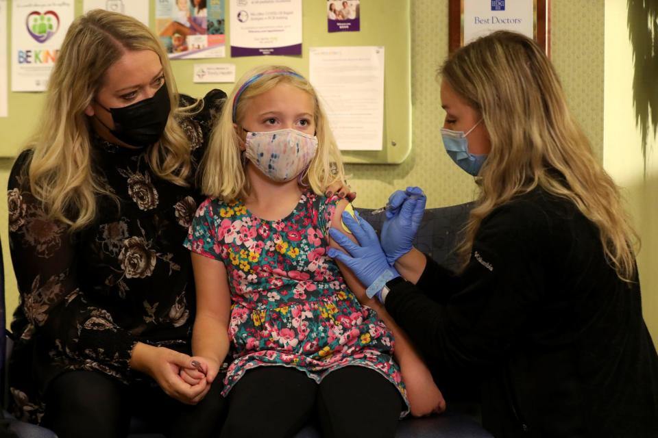 Rachael Nelson, left, holds the hand of her daughter, Clara Nelson, 7, as medical assistant Madison Peterson gives her the Pfizer coronavirus vaccine at the IHA Pediatrics medical office in Plymouth, Michigan, on Nov. 3, 2021. Federal regulators approved the vaccine for 5- to 11-year-olds Tuesday night.