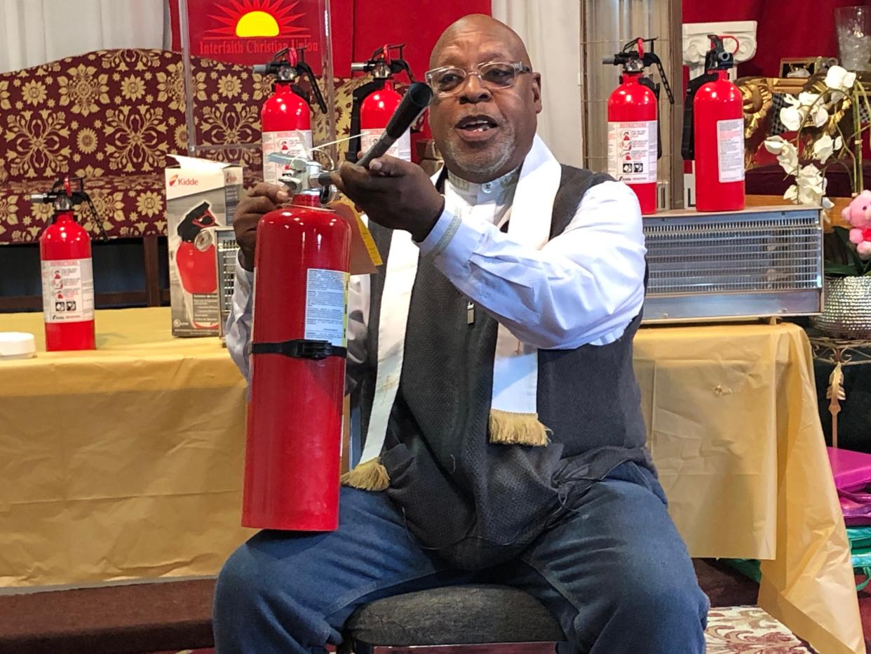 The Rev. Sylvester Williams shows off a fire extinguisher at the radio station he runs, WUBS-FM (89.7), in South Bend, on Thursday, Jan. 25, 2024, in a campaign to collect and distribute extinguishers to homes.