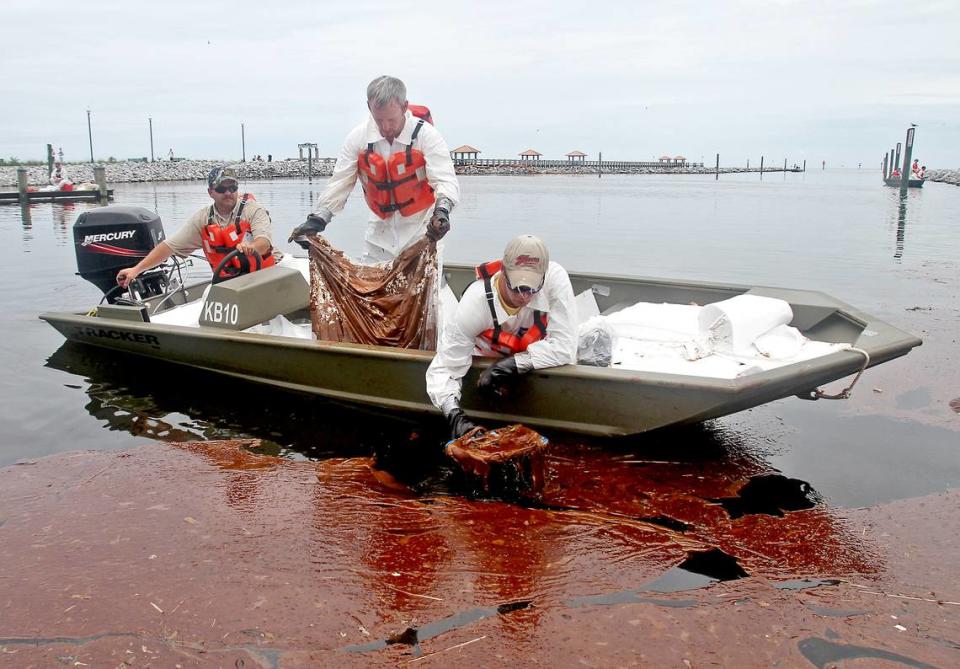 Workers skim a patch of weathered oil near a boat ramp in Gulfport, Mississippi, in July 2010.