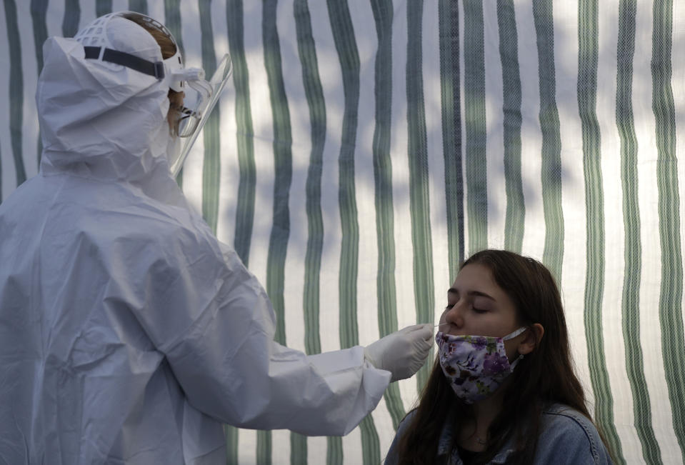 A woman gets tested for COVID-19 at a sampling station in Prague, Czech Republic, Monday, Sept. 21, 2020. The country coped well with the first wave of the coronavirus infections in the spring but has been facing a record surge of the new confirmed cases last week. (AP Photo/Petr David Josek)