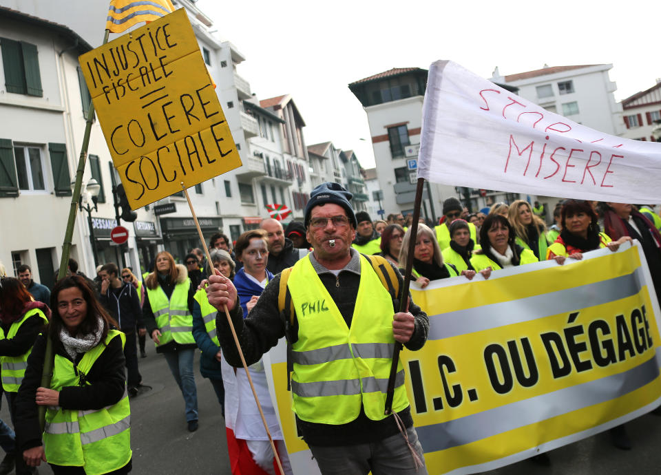 A yellow vest protester holds a placard reading " Social anger" during a demonstration in Saint Jean De Luz, France, Saturday, Jan. 19, 2019. Yellow vest protesters are planning rallies in several French cities despite a national debate launched this week by President Emmanuel Macron aimed at assuaging their anger.(AP Photo/Bob Edme)