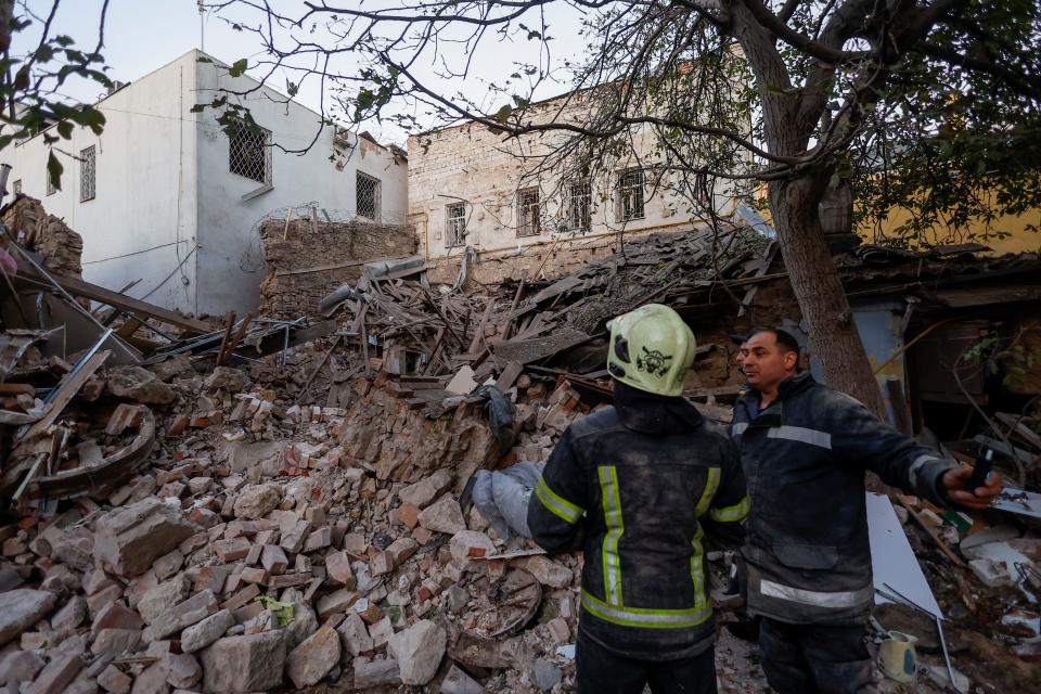 Rescuers stand next to a building heavily damaged by a Russian missile strike (REUTERS)