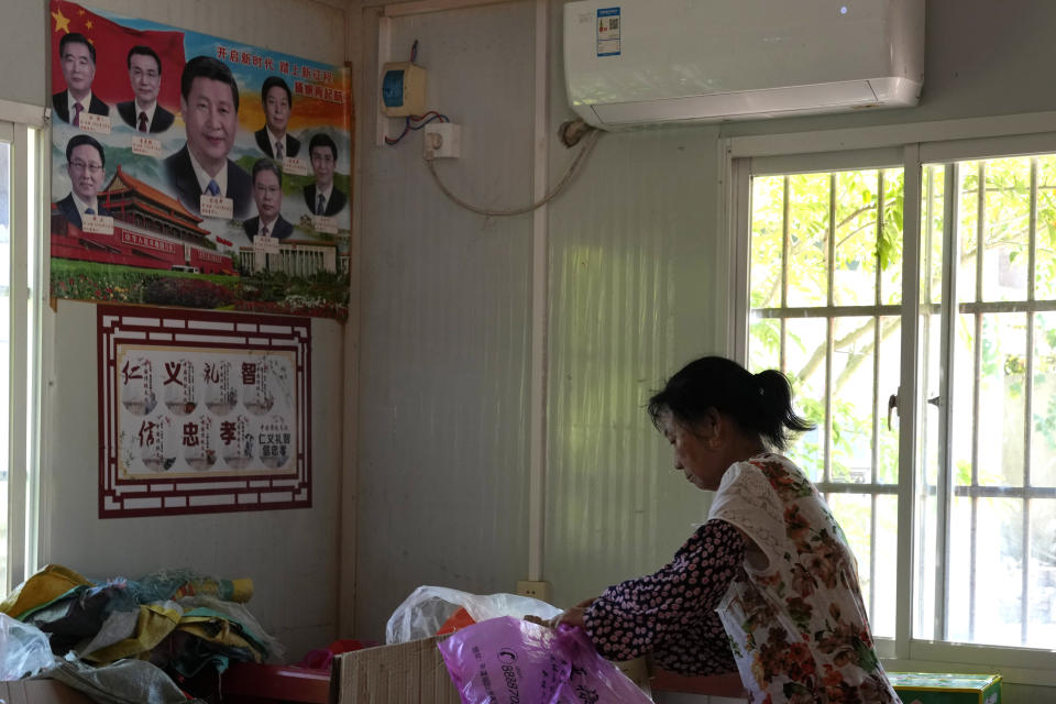 A woman sorts out supplies near a poster showing Chinese leaders including Chinese President Xi Jinping in Pingtan in eastern China's Fujian province, Saturday, Aug. 6, 2022. Taiwan said Saturday that China's military drills appear to simulate an attack on the self-ruled island, after multiple Chinese warships and aircraft crossed the median line of the Taiwan Strait following U.S. House Speaker Nancy Pelosi's visit to Taipei that infuriated Beijing. (AP Photo/Ng Han Guan)