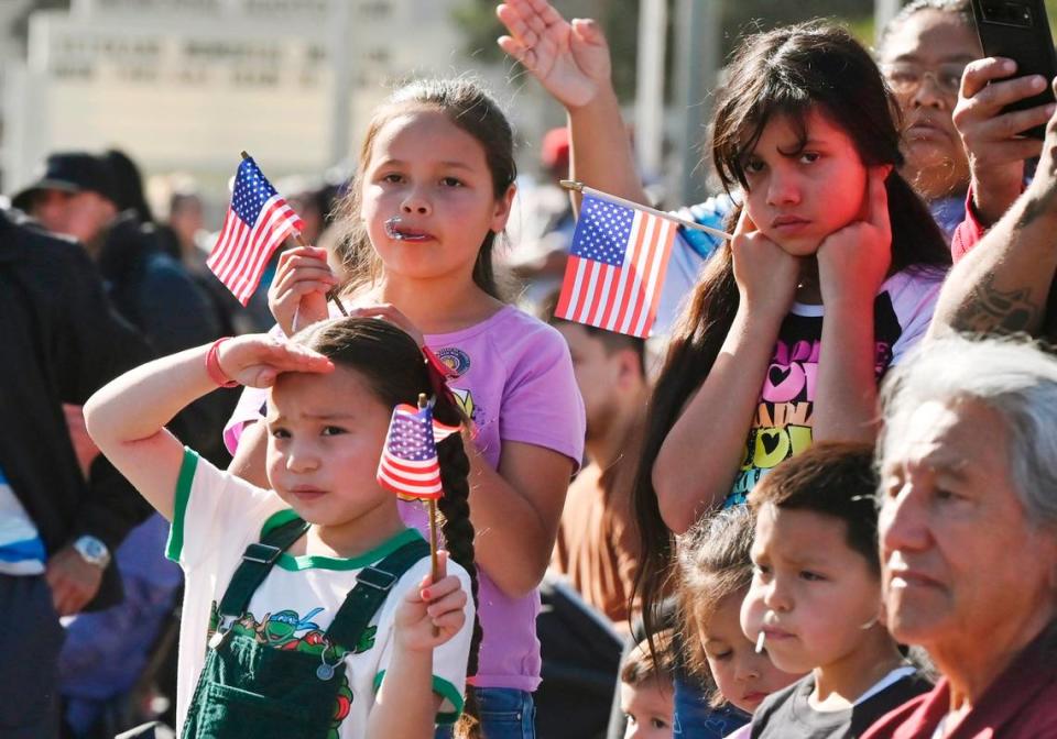 Children wave flags as the annual Central Valley Veterans Day Parade passes by Saturday, Nov. 11, 2023 in downtown Fresno.
