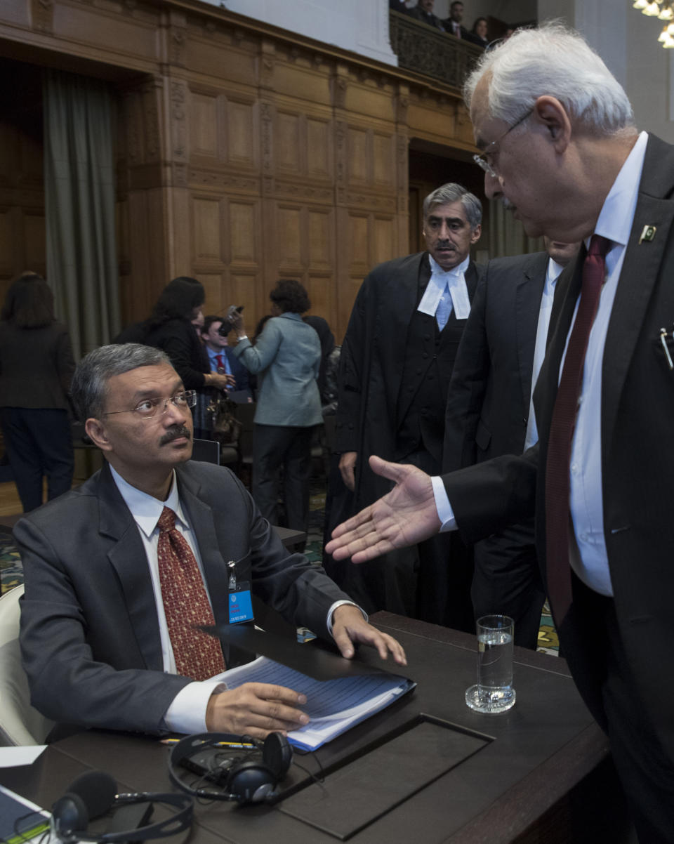 Pakistan's attorney general Anwar Mansoor Khan, right, greets Deepak Mittal, the joint secretary of India's Foreign Ministry, prior to India presenting oral arguments at the International Court of Justice, or World Court, in The Hague, Netherlands, Monday, Feb. 18, 2019. India is taking Pakistan to the United Nations' highest court in an attempt to save the life of an Indian naval officer sentenced to death last month by a Pakistani military court after being convicted of espionage.(AP Photo/Peter Dejong)