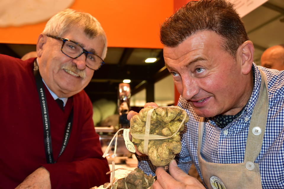 In this photo taken on Saturday, Nov. 9, 2019, Davide Curzietti, right, shows off a 730-gram truffle to judge Natale Romagnolo at the Alba Truffle Fair, established as a place to trade the highly prized and aromatic white truffles that grow in the hills around the southern Piedmont town of Alba in northern Italy. (AP Photo/Martino Masotto)