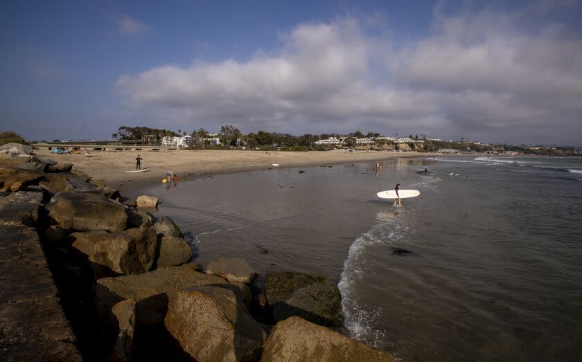 Dana Point, CA - October 12: A surfer heads out near the location of a proposed Doheny Desalination plant that is proposed by the South Coast Water District and be built on its property, roughly 1,500 feet from the shoreline in Dana Point. The pipes and slant wells will run from the property, underneath the Doheny State Beach Campground and into the ocean in Dana Point, Wednesday, Oct. 12, 2022. The California Coastal Commission is expected to approve plans for a new desalination plant during a meeting on Thursday. The Doheny Desalination plant could produce up to five million gallons of potable drinking water a day by 2027. The plant would use a subsurface slant well, drawing ocean water into the desalination plant from below the ocean floor. The South Coast Water District is working to obtain all major permits by the end of the year. (Allen J. Schaben / Los Angeles Times).