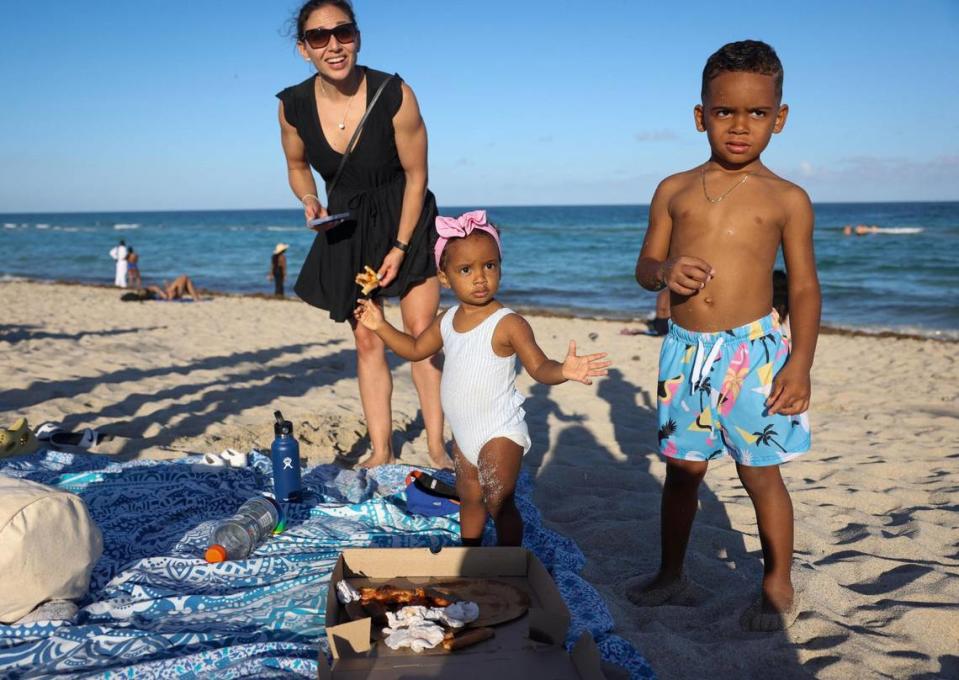 Whitney Peterson, left, visiting from Charlotte, North Carolina, for work, and her children Malia, 1, center, and Amari, 4, look at the seagulls flying through the sky during spring break on Sunday, March 26, 2023, in Miami Beach.