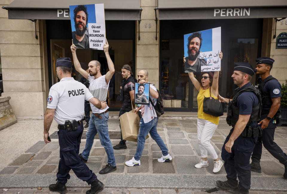 Police officers escort Isabel Leclercq, right, the mother of missing traveler Yann Bourdon in Egypt as she holds a picture of her son during during a march with relatives and friends near the Elysee Palace during Egyptian President Abdel Fattah el-Sissi visiting French President Emmanuel Macron in Paris, Friday, July 22. The family of a French backpacker who went missing in Egypt have used a visit to Paris by the Egyptian president to press for an investigation into his disappearance. Placards reads, where is Yann Bourdon, President Sissi. (AP Photo/Thomas Padilla)