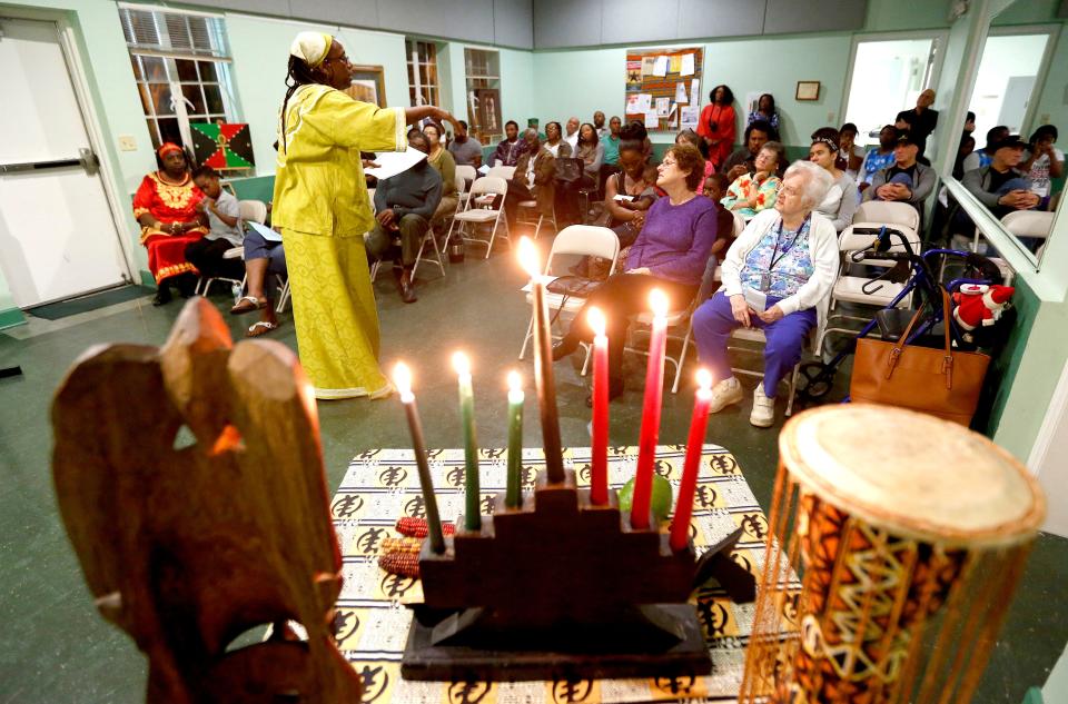 NKWanda Jah recites a poem in front of the seven lit candles during a community Kwanzaa Celebration at the Wilhelmina Johnson Center hosted by the Cultural Arts Coalition several years ago in Gainesville. Each of the seven days of Kwanzaa is focused on one of the seven traditional principles including unity, self determination, collective work and responsibility, cooperative economics, purpose, creativity and faith [File photo by Matt Stamey/Special to The Guardian]