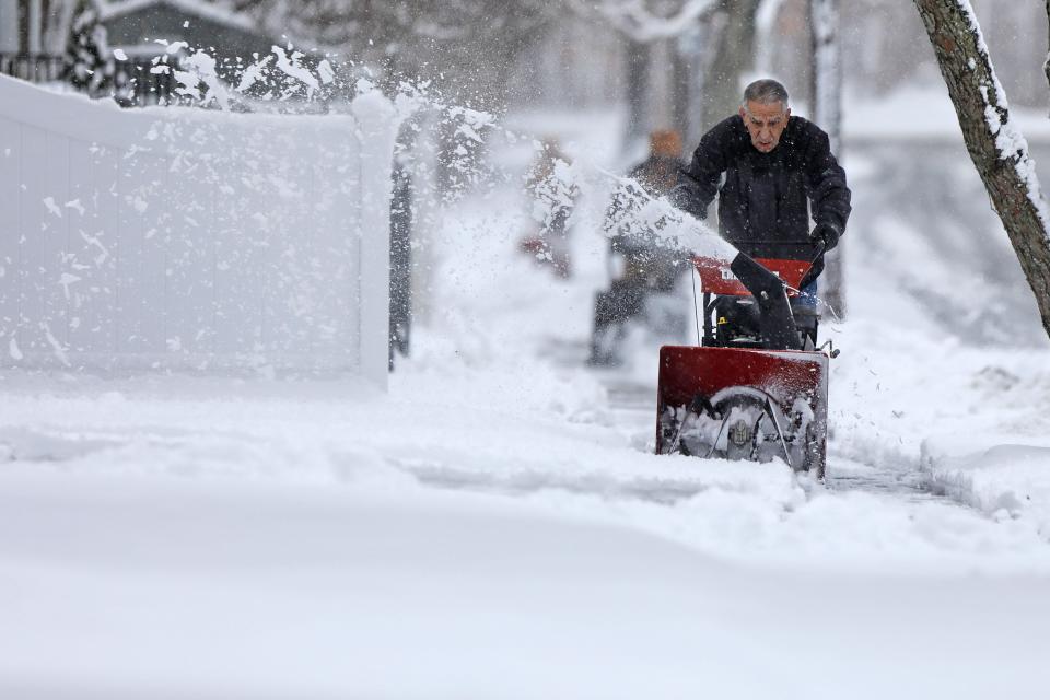 Don Perry uses a snowblower to clear the snow from the sidewalk in front of his home in New Bedford.