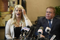 Chelsea Romo, left, pulls the her hair out of the way to show her left eye at a news conference as her attorney James Frantz looks on Thursday, Oct. 3, 2019, in San Diego. Romo lost her left eye in the Las Vegas shooting. Two years after a shooter rained gunfire on country music fans from a high-rise Las Vegas hotel, MGM Resorts International reached a settlement that could pay up to $800 million to families of the 58 people who died and hundreds of others who were injured, attorneys announced Thursday. (AP Photo/Denis Poroy)
