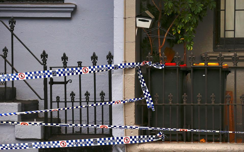 Police tape can be seen attached to the front fence of a home being searched after Australian counter-terrorism police - Credit: REUTERS/David Gray