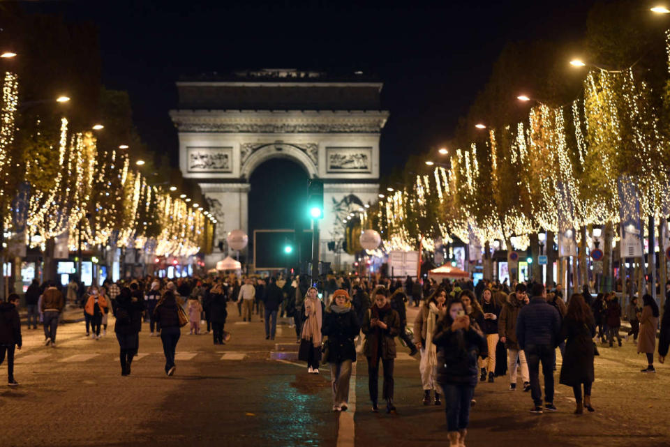 People walk along the Champs-Elysees avenue after the inauguration of the Christmas decorations in Paris on November 20, 2022. (Photo by JULIEN DE ROSA / AFP)