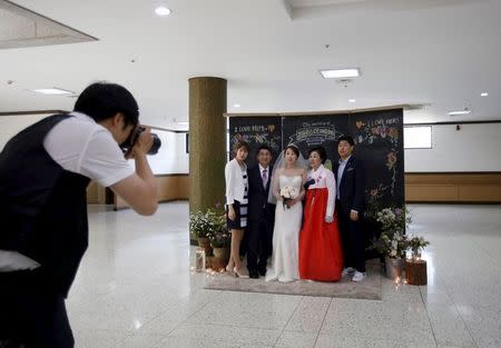 A bride posse for photographs with her family before a wedding ceremony at a budget wedding hall at the National Library of Korea in Seoul, South Korea, May 16, 2015. REUTERS/Kim Hong-Ji