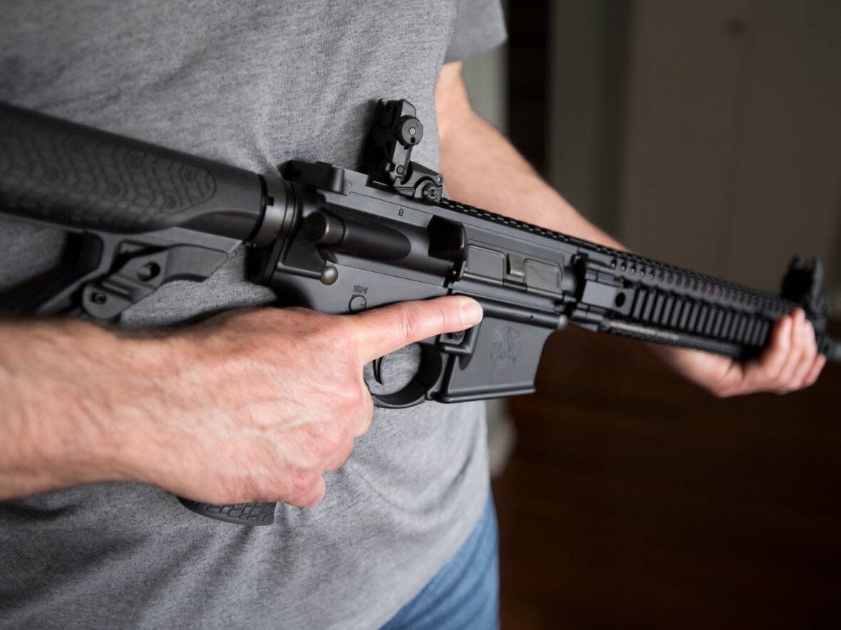 A restricted gun licence holder holds a AR-15 at his home in Langley, B.C., on May 1, 2020. (Jonathan Hayward/The Canadian Press - image credit)