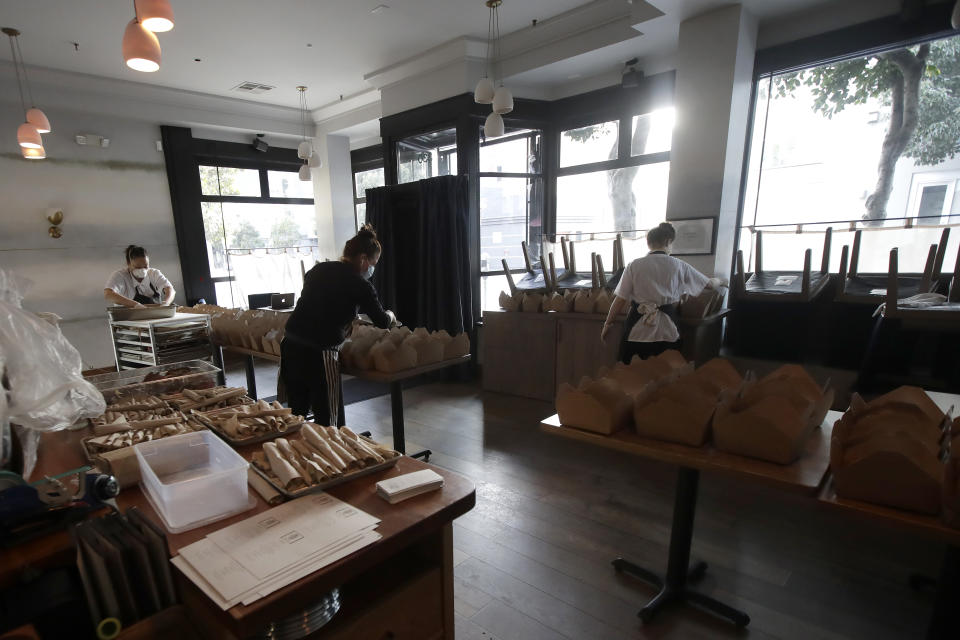 In this Friday, March 27, 2020, photo, Nightbird Restaurant sous chef Bailey Walton, from left, chef and owner Kim Alter and pastry chef Hope Waggoner pack dinner boxes that were delivered to hospital workers in San Francisco. A group of tech-savvy, entrepreneurial San Francisco friends wanted to help two groups devastated by the coronavirus pandemic. They came up with a plan that involved soliciting donations, tapping friends in the restaurant world and getting San Francisco hospitals to accept free food cooked up by some of the city's top chefs. (AP Photo/Jeff Chiu)