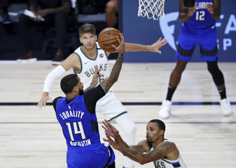 Orlando Magic guard D.J. Augustin (14) shoots in front of Milwaukee Bucks guard George Hill (3) during the second half of Game 1 of an NBA basketball first-round playoff series, Tuesday, Aug. 18, 2020, in Lake Buena Vista, Fla. (Kim Klement/Pool Photo via AP)
