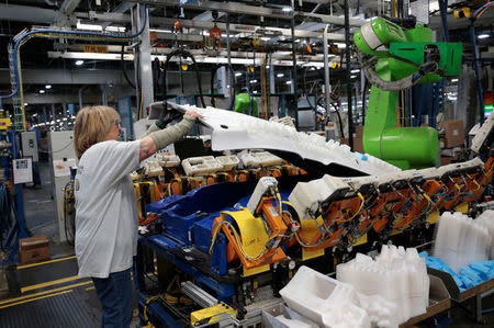 A General Motors assembly worker removes a Headliner after a Collaborative Robot applied hot glue and HIC plastic caps, intended for 2018 Chevrolet Bolt EV and Sonic vehicles, at Orion Assembly in Lake Orion, Michigan, U.S., March 19, 2018. REUTERS/Rebecca Cook/Files