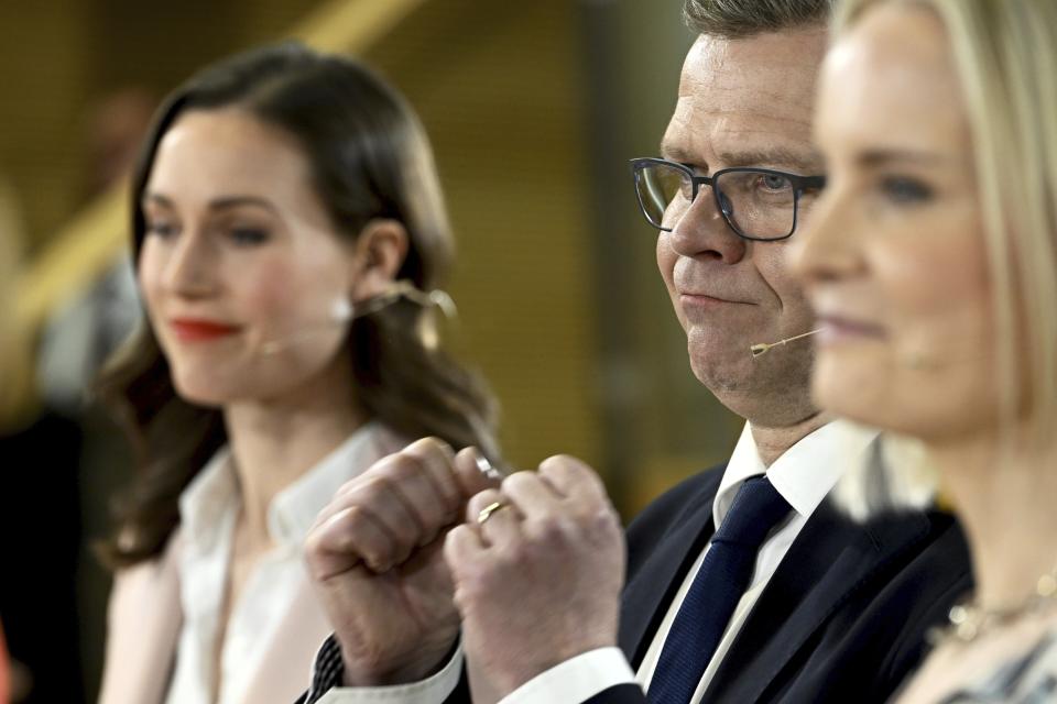 Chair of SDP Sanna Marin, left, and chair of The Finns party Riikka Purra, right, look on as National Coalition Party chair Petteri Orpo cheers at the Finnish parliamentary elections media reception at the Finnish Parliament in Helsinki, Finland on Sunday, April 2, 2023. (Heikki Saukkomaa/Lehtikuva via AP)